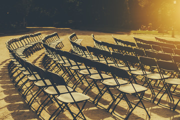 Empty seat rows of folding chairs on ground before a event parallel and rounded arranged, multiple...