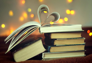Opened book with heart shaped pages with lights glowing background