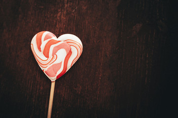 Heart shaped lollipop on a rustic wooden table with copy space.