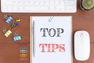 Text Top tips on white paper which has keyboard mouse pen and office equipment on wood background /...