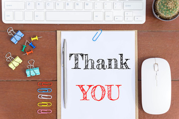 Text Thank you on white paper which has keyboard mouse pen and office equipment on wood background / business concept.