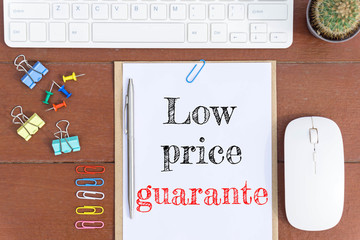 Text Low price guarantor on white paper which has keyboard mouse pen and office equipment on wood background / business concept.