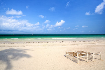 Fototapeta na wymiar White sand beach with wooden deck chairs in Zanzibar
