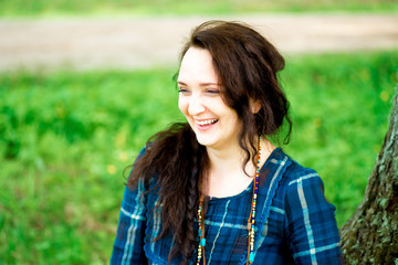 Fototapeta premium Happy attractive girl sitting on a green lawn in the park on a s