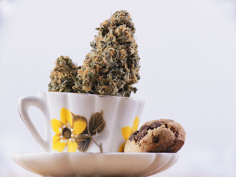 Detail of cannabis nug and coffee cup with chocolate chip cookie