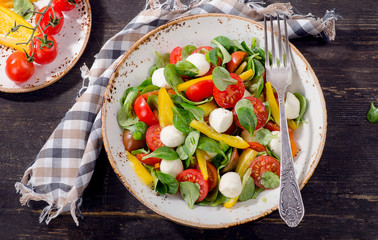 Salad with mozzarella on a rustic wooden table.