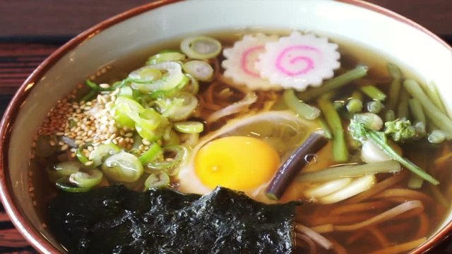 Japanese soba noodle hot soup with green onion, naruto, seaweed and raw egg
