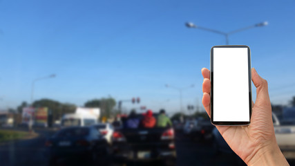 Hand holding mobile smart phone with interface on road background