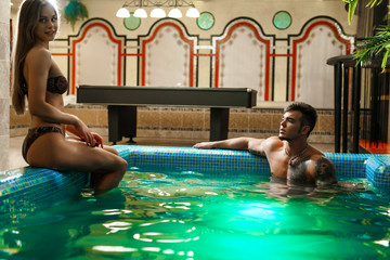 Obraz na płótnie Canvas Young sexy pair bathing in luxurious swimming pool