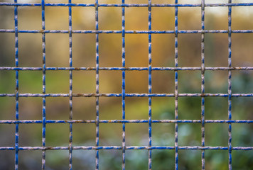 Steel and rusty grid fence with blurred background
