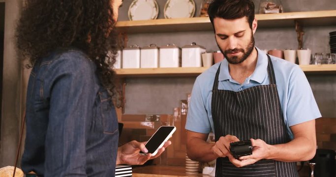 Woman paying bill with her smartphone in caf&Atilde;&copy; 4k