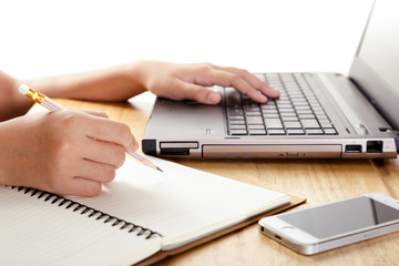 Fototapeta premium Girl's hands writing in notebook and using laptop.