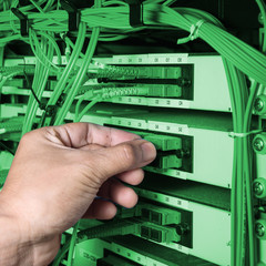 man connecting fiber optic cable to core switch
