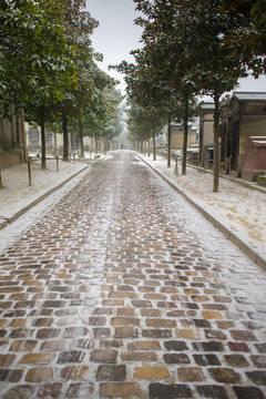 Paris, the Pere-Lachaise cemetery, paved street under snow in winter 