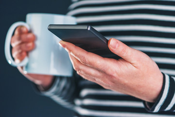 Morning coffee drink and mobile phone in female hands