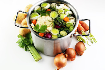 Broth with carrots, onions various fresh vegetables in a pot - c