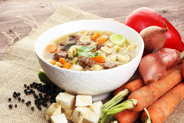 Clear soup with beef and noodles. Broth with carrots, onions var