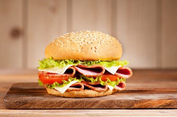 Sandwich with ham, cheese and vegetables on a rustic background