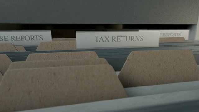 A closeup view of a filing cabinet drawer opening to reveal income tax related documents inside