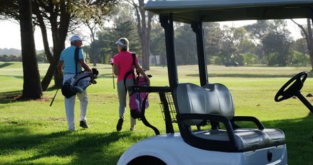 Two golfers walking together with golf bag at golf course 