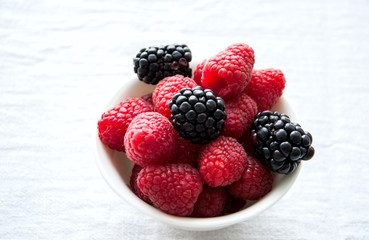 Fresh raw berries in a white bowl on a table