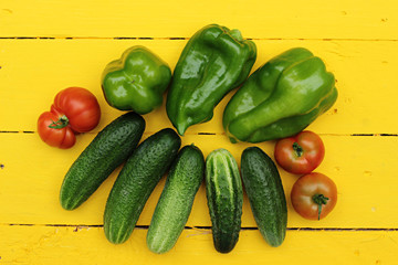 green peppers, cucumbers and tomatoes on a yellow wooden background 1