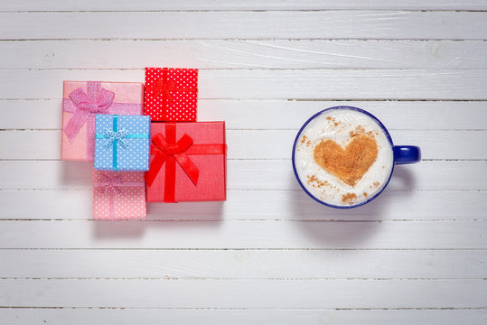 Cups of coffee with heart shape symbol and gift boxes 