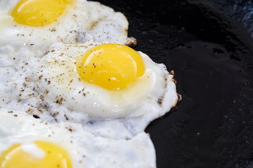 Fried eggs in a frying pan. Process of cooking eggs closeup. Food Background
