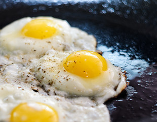 Fried eggs in a frying pan. Process of cooking eggs closeup. Food Background
