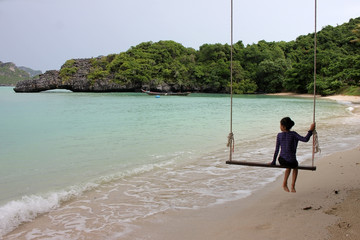 Asian girl sitting on the cradle on the beach. 