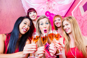 Braut und Freundinnen feiern Junggesellinnenabschied mit Sekt im Nachtclub