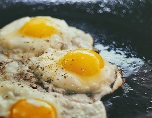 Vintage photo of Fried eggs in a frying pan. Process of cooking eggs closeup. Food Background