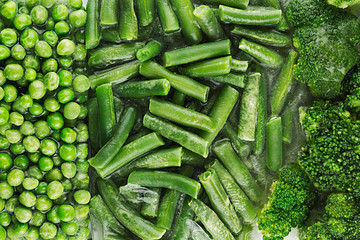 Assortment of fresh frozen green peas, french bean, broccoli with hoarfrost closeup as background. Healthy vitamin food.