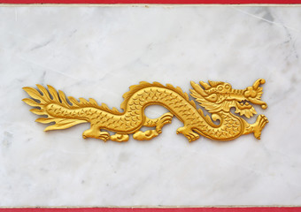 Fototapeta premium Traditional golden chinese dragon wood carved against marble background
