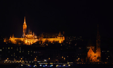 Fototapeta na wymiar View on the illuminated Fisherman's Bastion and Calvinist Church on a winter night, surrounded by many lightened windows. Budapest