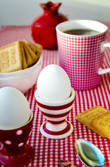 Hard boiled eggs, tea and cookies served in the dotted, striped and checkered red and white crockery