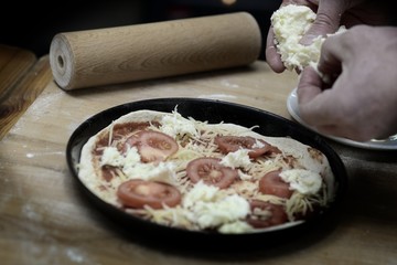 Hände arbeiten an einer Pizza