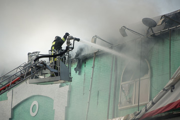 Firefighters in action fighting, extinguishing fire, in smoke.