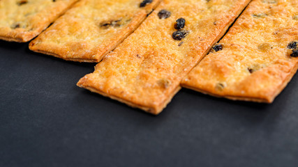 Sweet cookies with raisins. Pastry strips on black background.