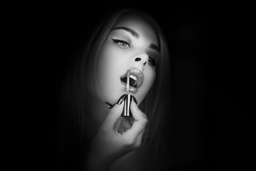 Beautiful girl Applying lipstick. Young Woman putting  lipstick. Black and white
