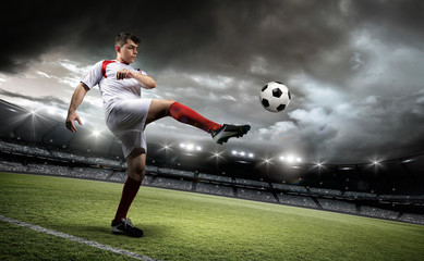 Football player is kicking a ball in the stadium.