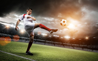 Fototapeta na wymiar Football player is kicking a ball in the stadium.