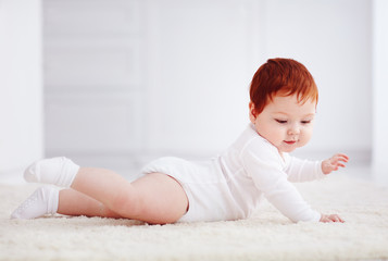 happy, nine months old baby crawling on carpet at home