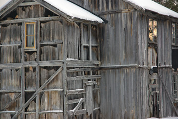 Nahaufnahme von verfallenem Holzhaus mit verwitterter Fassade und schneebedecktem Dach