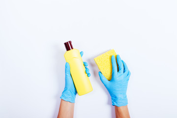 Female hands in blue rubber gloves holding a yellow bottle of de