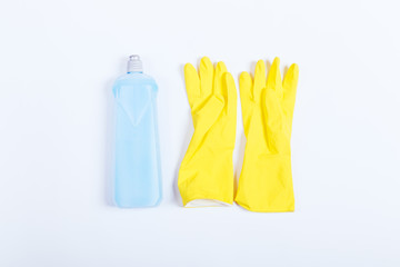 Yellow rubber gloves and a blue bottle of detergent on white bac