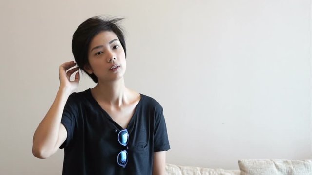 Asian hipster woman setting her hair and wearing sunglasses