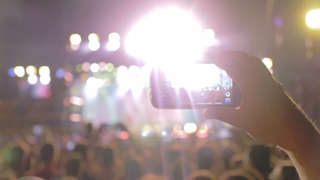 boy's hand filming a concert in the crowd