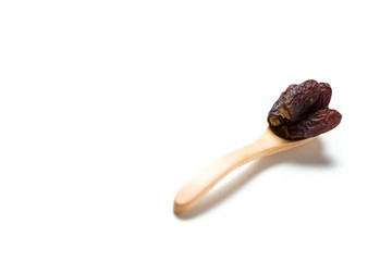 A dried dates in a wooden spoon isolated over white background
