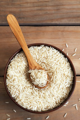 Raw uncooked basmati rice in wooden bowl. Top view with copy space